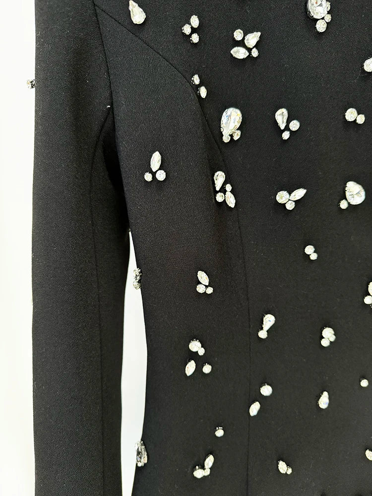 Black dress with white embellishments on a hanger against a white background