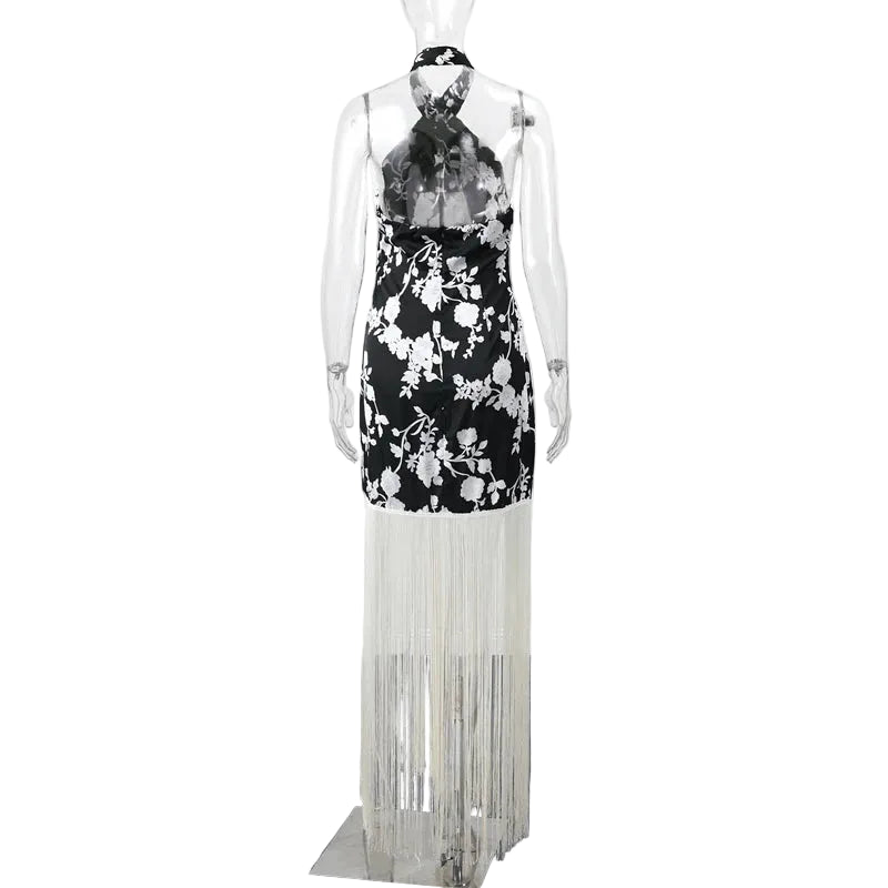 Mannequin wearing a black floral dress with white fringe on a plain background