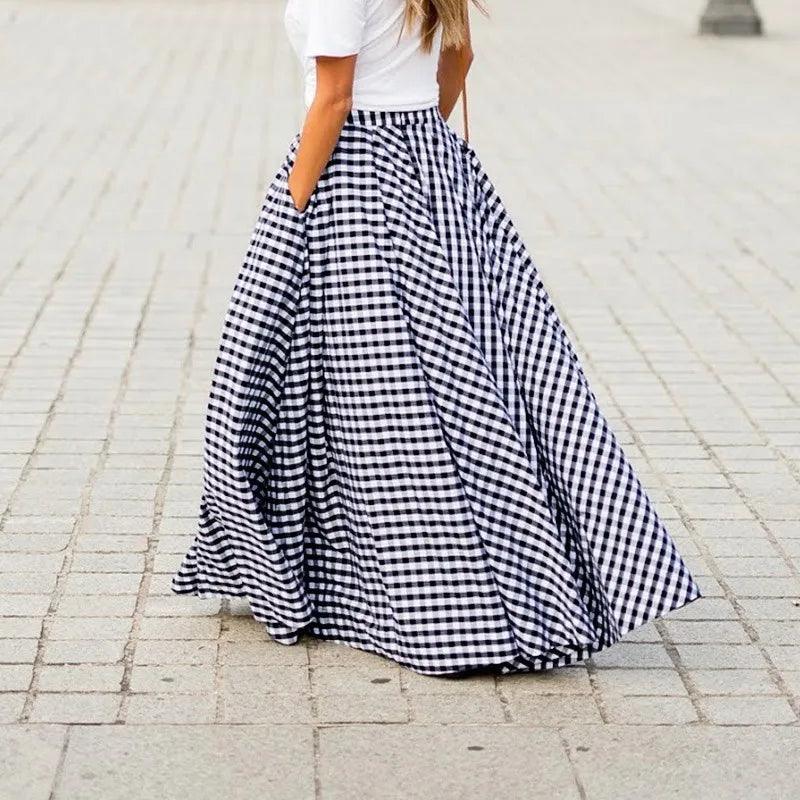 Person wearing a long black and white checkered skirt on a paved street.