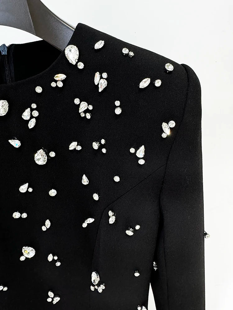 Black dress with white embellishments on a hanger against a white background