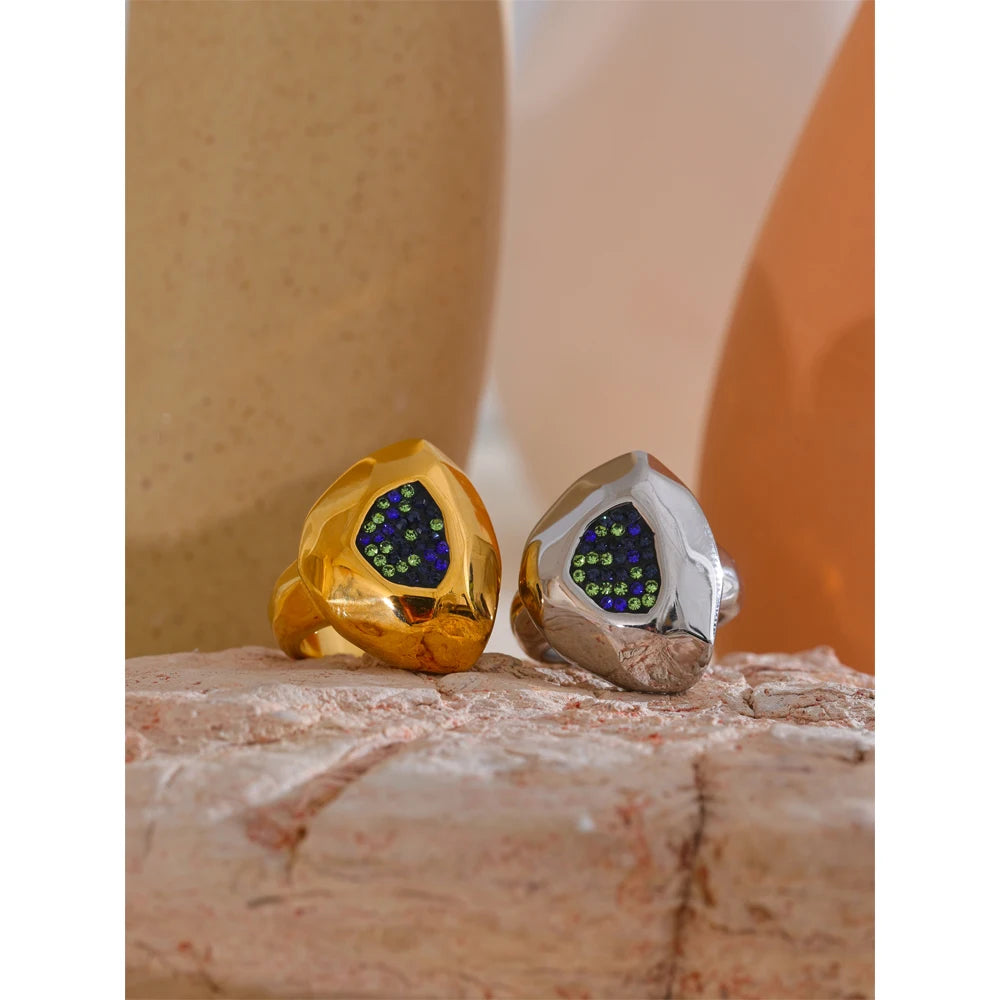 Gold and silver earrings with green gemstones on a textured surface
