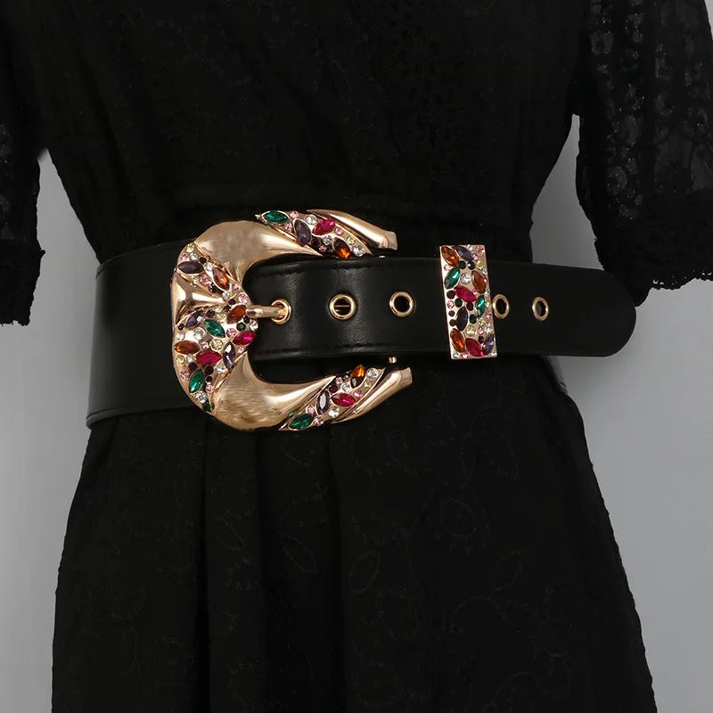 Black belt with a gold buckle featuring colorful gemstones on a black outfit.