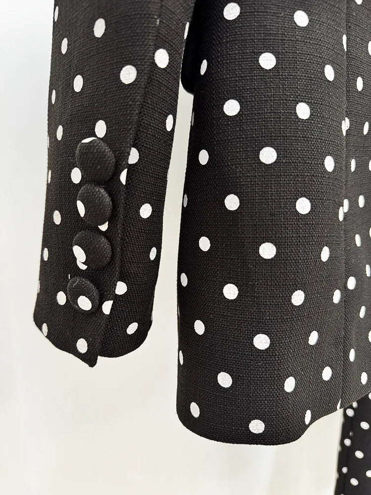 Black polka dot dress with pom-pom details on a white background