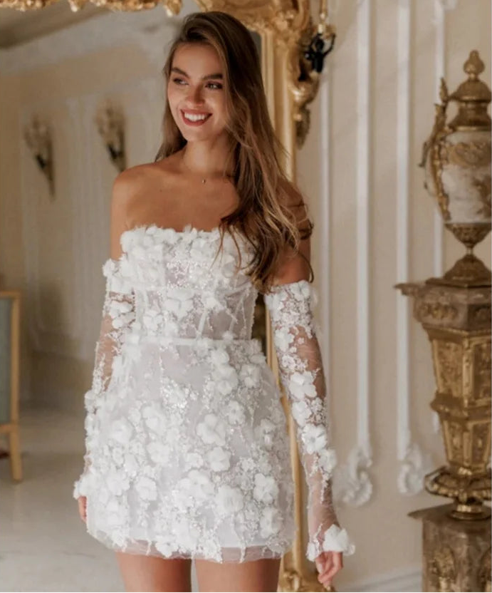 Woman wearing a white lace dress with floral details in an elegant room.