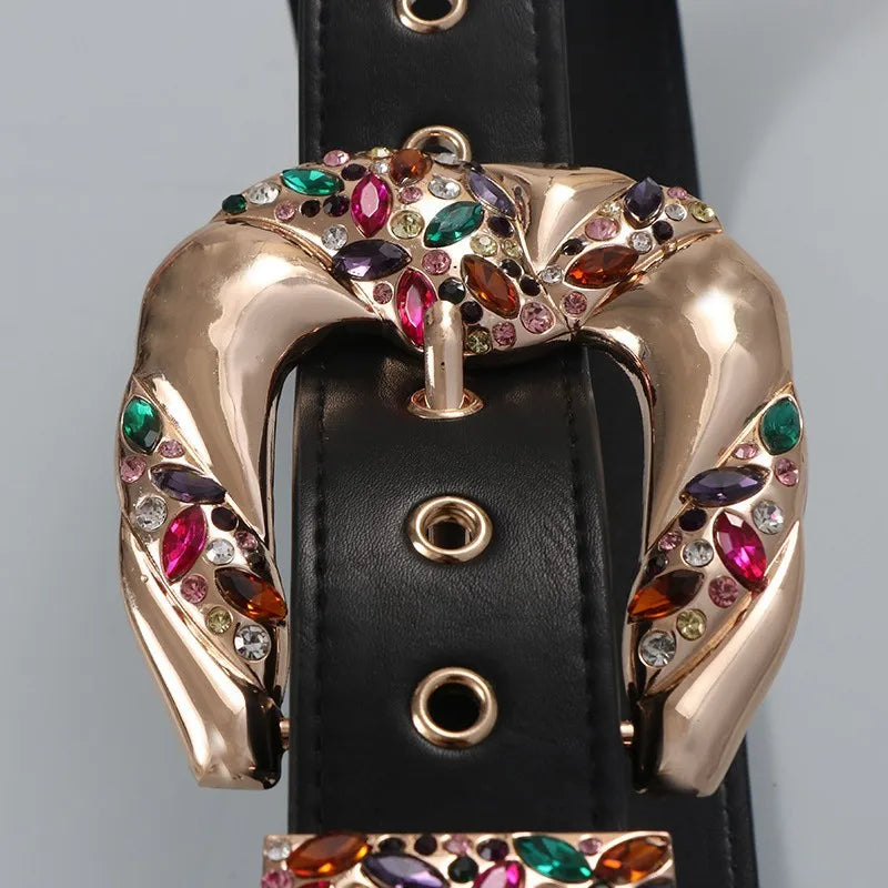 Decorative belt buckle with colorful gemstones on a black belt against a gray background