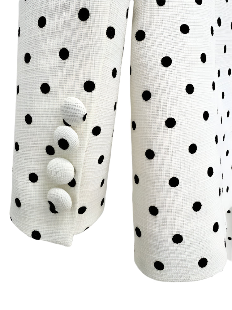 White linen fabric with black polka dots and white buttons on a light gray background
