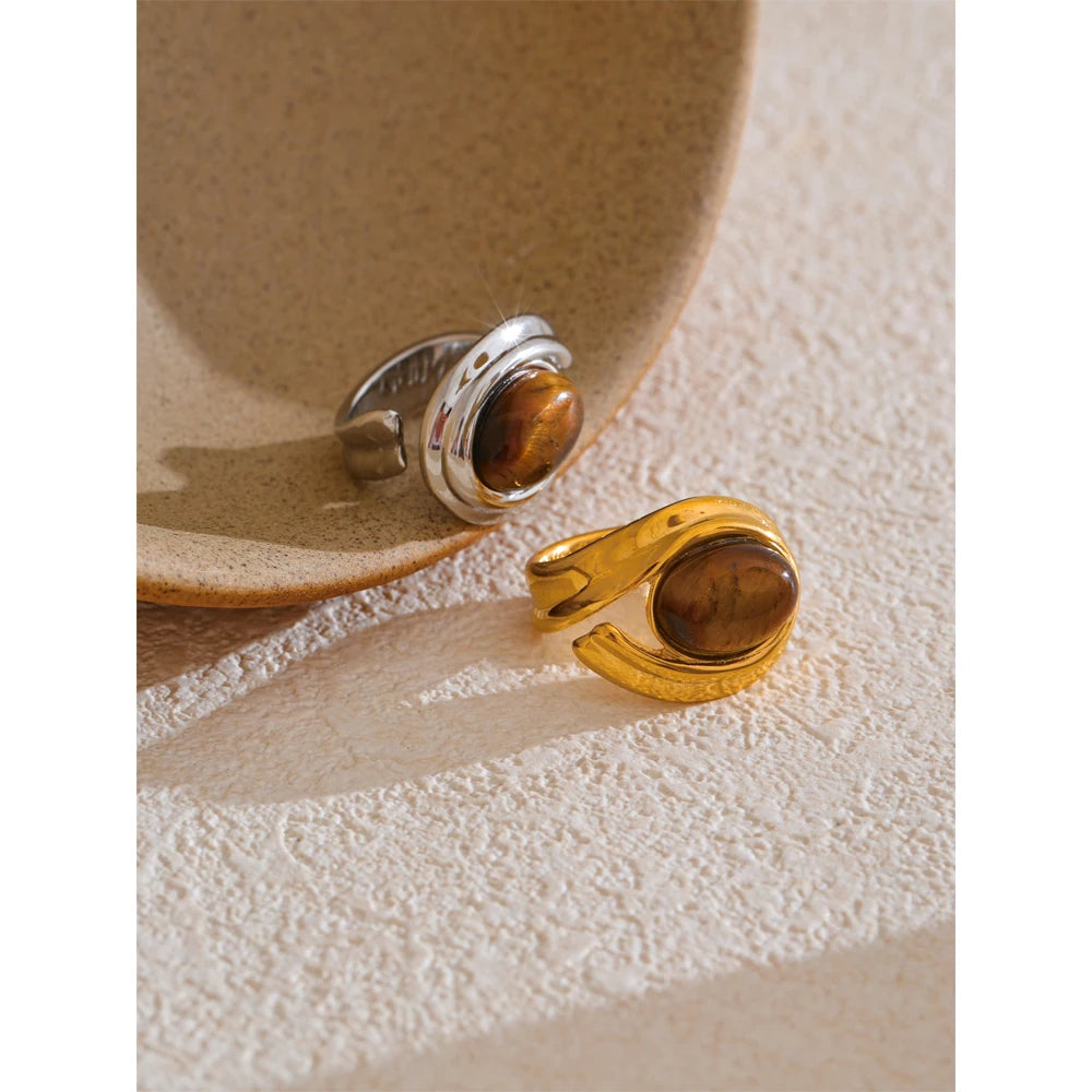 Gold and silver ring with tiger's eye stone on a textured surface