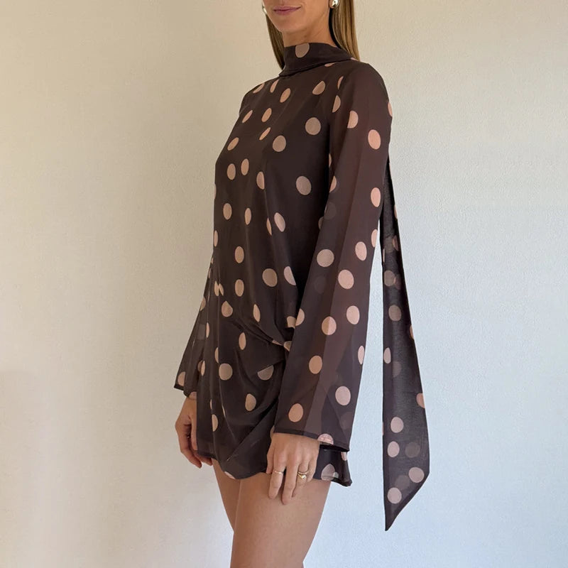 Woman wearing a brown dress with pink polka dots against a plain background